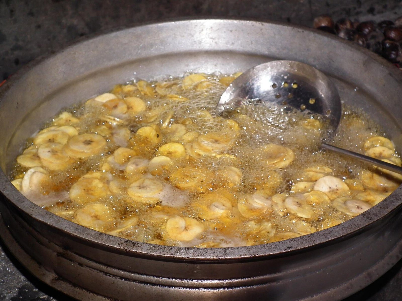 Banana chips being fried the traditional way in an uruli