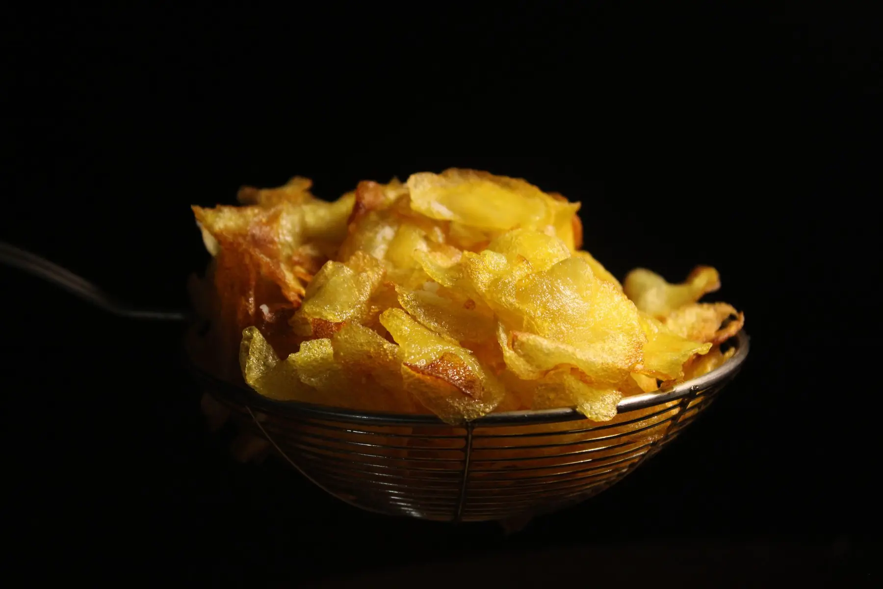 Golden chips freshly lifted from the oil in a frying basket